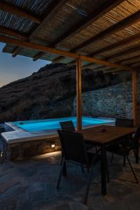 un patio con mesa y sillas y una piscina en Epithea Suites Kythnos 5 με ιδιωτική πισίνα en Kíthnos