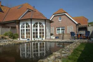 una casa con un estanque frente a una casa en Ferienhaus Inselliebe en Borkum