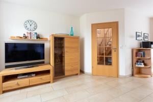 ein Wohnzimmer mit einem TV und einer Uhr an der Wand in der Unterkunft Ferienhaus Inselliebe in Borkum