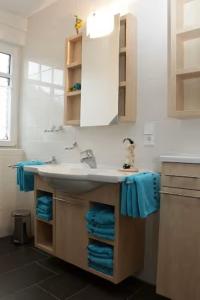 a bathroom with a sink and blue towels at Ferienhaus Inselliebe in Borkum
