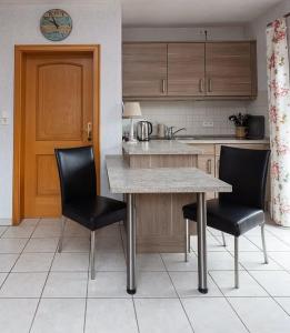 een keuken met een tafel en twee zwarte stoelen bij Ferienhaus Inselkate in Borkum