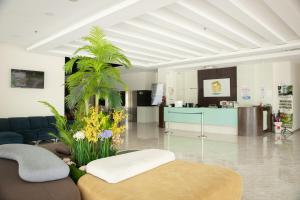 a living room with a couch and a palm tree at Golden Roof Hotel Ampang Ipoh in Ipoh