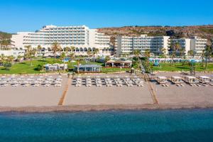 eine Luftansicht auf einen Strand mit Stühlen und Gebäuden in der Unterkunft Rodos Palladium Leisure & Wellness in Faliraki