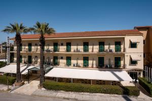 a large building with palm trees in front of it at Hotel Bretagne in Corfu