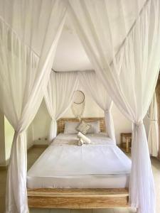 a bedroom with a canopy bed with white drapes at Green Coco House in Amed