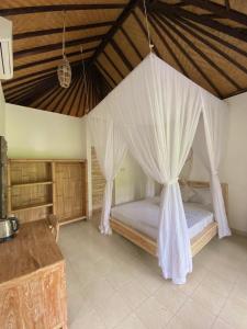 a bedroom with a bed with a mosquito net at Green Coco House in Amed