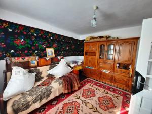 een slaapkamer met een bed en een muur met bloemen bij Casuta bunicilor 