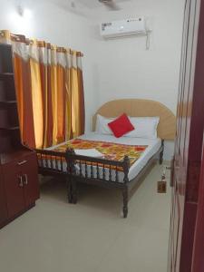 - une chambre avec un lit en bois et un oreiller rouge dans l'établissement Hilton Beach Home, à Alappuzha