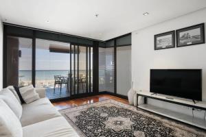 a living room with a white couch and a flat screen tv at The Sandpiper Sanctuary at Henley Beach in Henley Beach South