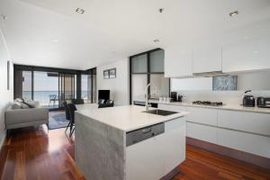 a kitchen with white cabinets and a kitchen island at The Sandpiper Sanctuary at Henley Beach in Henley Beach South