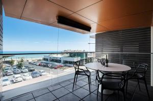 a balcony with a table and chairs and a large window at The Sandpiper Sanctuary at Henley Beach in Henley Beach South