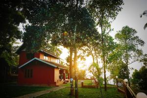 a red house with the sun shining through some trees at Mistil Garden Resort in Kozhikode