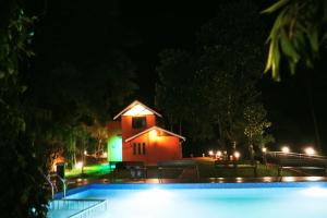 a house at night with a swimming pool at Mistil Garden Resort in Kozhikode