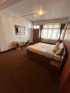 um quarto com uma cama grande e uma janela em The Valaya Hotel em Darjeeling
