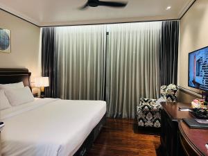 een slaapkamer met een bed, een bureau en een televisie bij Hotel du Monde Art in Hanoi