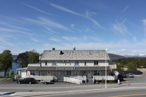 a building on the side of a road next to a street at Ulvsvåg Gjestgiveri og Fjordcamping AS in Ulvsvåg