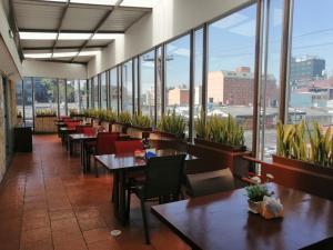 - un restaurant avec des tables, des chaises et de grandes fenêtres dans l'établissement Hotel AW Boutique, à Bogotá