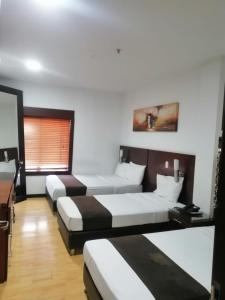 Habitación con 3 camas, escritorio y mesa. en Hotel AW Boutique, en Bogotá
