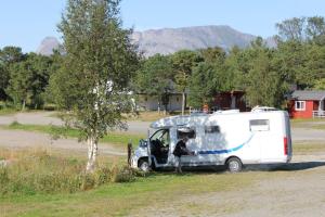 a man is standing next to a caravan at Ulvsvåg Gjestgiveri og Fjordcamping AS in Ulvsvåg