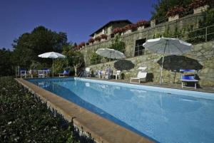 einen Pool mit Sonnenschirmen und Stühlen neben einem Gebäude in der Unterkunft Ferienhaus für 12 Personen in Capannori, Toskana Provinz Lucca - b63292 in Petrognano