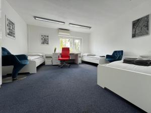 1 dormitorio con 2 camas y silla roja en Mieterlux Frankfurt Heusenstamm 46, en Heusenstamm