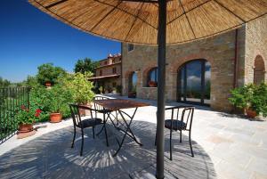 una mesa y sillas bajo una sombrilla en un patio en Ferienhaus mit Privatpool für 10 Personen ca 200 qm in Civitella in Val di Chiana, Toskana Provinz Arezzo, en Civitella in Val di Chiana