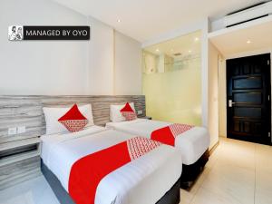 2 letti in camera d'albergo con accenti rossi di Super OYO Flagship 90775 I Sleep Hotel Bandung a Bandung