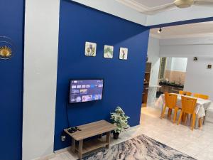 un mur bleu dans un salon avec une table dans l'établissement Serene Bukit Beruang Cottage 4 ROOMS FULL AIRCOND & NETFLIX by EZYROOM MELAKA, à Ayer Keroh
