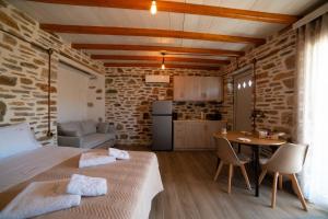 a room with a bed and a table and a kitchen at Epithea Suites Kythnos Keli in Kithnos