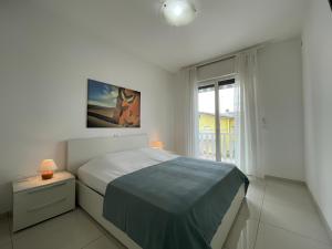 um quarto branco com uma cama e uma janela em Appartamento Al Faro I TerraceRelax&Parking em Lignano Sabbiadoro