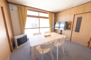 a room with a table with chairs and a television at +C FURANO in Furano