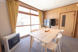 Zimmer mit einem Tisch und einem TV sowie einem Tisch und Stühlen in der Unterkunft +C FURANO in Furano