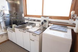 eine kleine Küche mit einem Waschbecken und einem Fenster in der Unterkunft +C FURANO in Furano