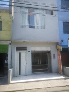 a white building with a door and a window at Hostal El Conde in Tacna