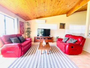 a living room with red furniture and a flat screen tv at Aircabin - Tuggerawong - Lake Front - 3 Beds House in Rocky Point