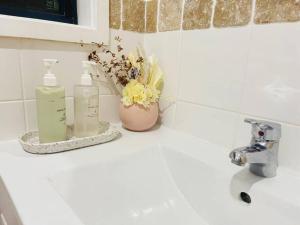 een wastafel in de badkamer met 2 flessen zeep en bloemen bij Aircabin - Tuggerawong - Lake Front - 3 Beds House in Rocky Point