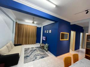 un salon avec un mur d'accent bleu dans l'établissement Serene Bukit Beruang Cottage 4 ROOMS FULL AIRCOND & NETFLIX by EZYROOM MELAKA, à Ayer Keroh