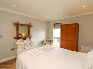 1 dormitorio con cama blanca y espejo en Puffin View en Seahouses