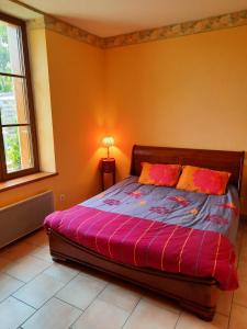 Schlafzimmer mit einem Bett mit rosa Bettwäsche und einem Fenster in der Unterkunft Gîte de l'école in Pontlevoy