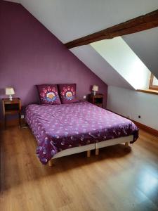 ein Schlafzimmer mit einem lila Bett im Dachgeschoss in der Unterkunft Gîte de l'école in Pontlevoy