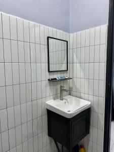 La salle de bains est pourvue de carrelage blanc, d'un lavabo et d'un miroir. dans l'établissement Homestay D'Pusu Tiga Kuala Terengganu, à Kuala Terengganu 32 autres photos