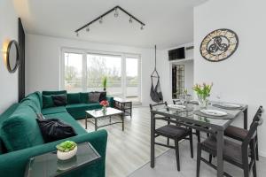a living room with a green couch and a table at Etna Apartments Kołobrzeg by Renters in Kołobrzeg