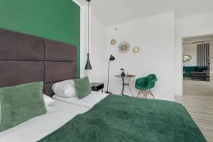 a bedroom with a large bed with a green blanket at Etna Apartments Kołobrzeg by Renters in Kołobrzeg
