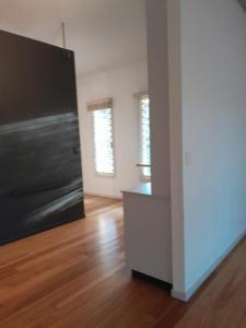 an empty living room with a black door and wooden floors at Bitolovo in Nimbin
