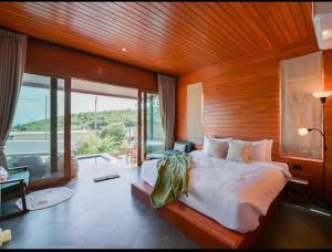 ein Schlafzimmer mit einem großen Bett und einem großen Fenster in der Unterkunft Phuzita Kohlarn-ภูศิตา เกาะล้าน in Ko Larn