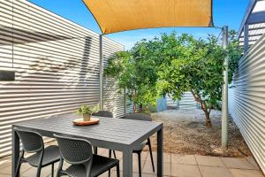ein Tisch und Stühle auf einer Terrasse mit einem Sonnenschirm in der Unterkunft 'The Cosy Corner' Classic Haven with Modern Comforts in Adelaide