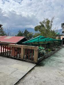 a vegetable stand with a green umbrella on a fence at Yesheyzz in Gangtok
