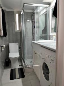 a bathroom with a toilet and a sink and a washing machine at NikhsHome in Loutraki
