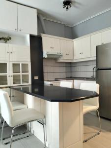 a kitchen with white cabinets and a black counter top at NikhsHome in Loutraki