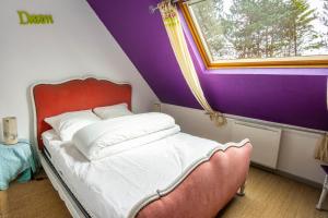 un letto in una camera con pareti viola e finestra di Bienvenue à Sainte Cécile Plage a Camiers